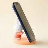 Orange bunny phone stand with white figurine and angled dark phone support
