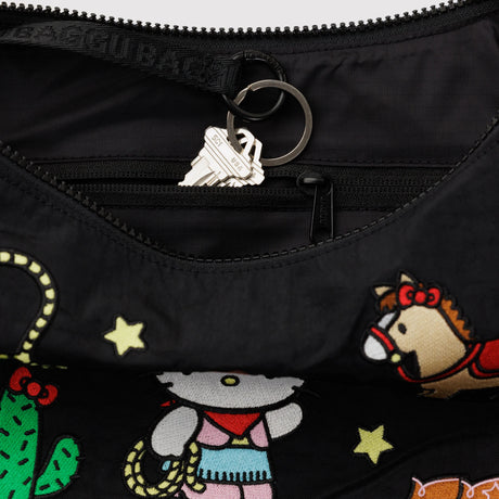 A close-up of a zippered inner pocket in the black Hello Kitty x Baggu Medium Nylon Crescent Bag - Western, with cartoon designs, showing a keychain with two keys partially inside.