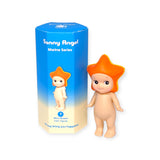 A collector's dream, this small figurine adorned with a starfish hat stands proudly next to a cylindrical box labeled with the brand Sonny Angel and the product name "Marine Series," enticing you to uncover which mystery figure is hidden inside.