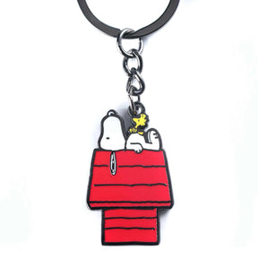 Metal enamel keychain of Snoopy lying on his classic red doghouse with Woodstock perched on top, white background.