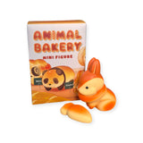 A charming orange bunny figure sits beside the delightful Dreams Inc "Animal Bakery Mini Figure" Blind Box, featuring enchanting illustrations of a sheep and a panda. As part of the Collectible Series, it's an ideal addition for fans who enjoy surprises and whimsical companions.