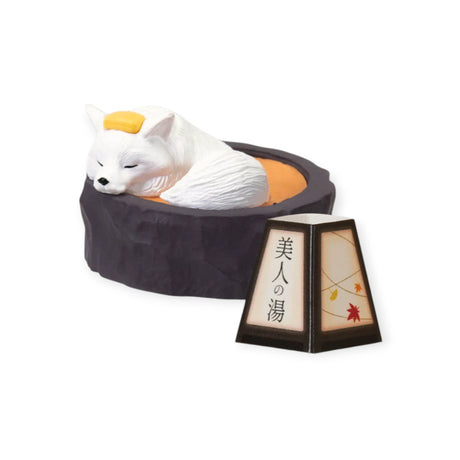 White fox figurine with yellow towel relaxing in black onsen tub beside autumn-themed lantern, gallery position 1