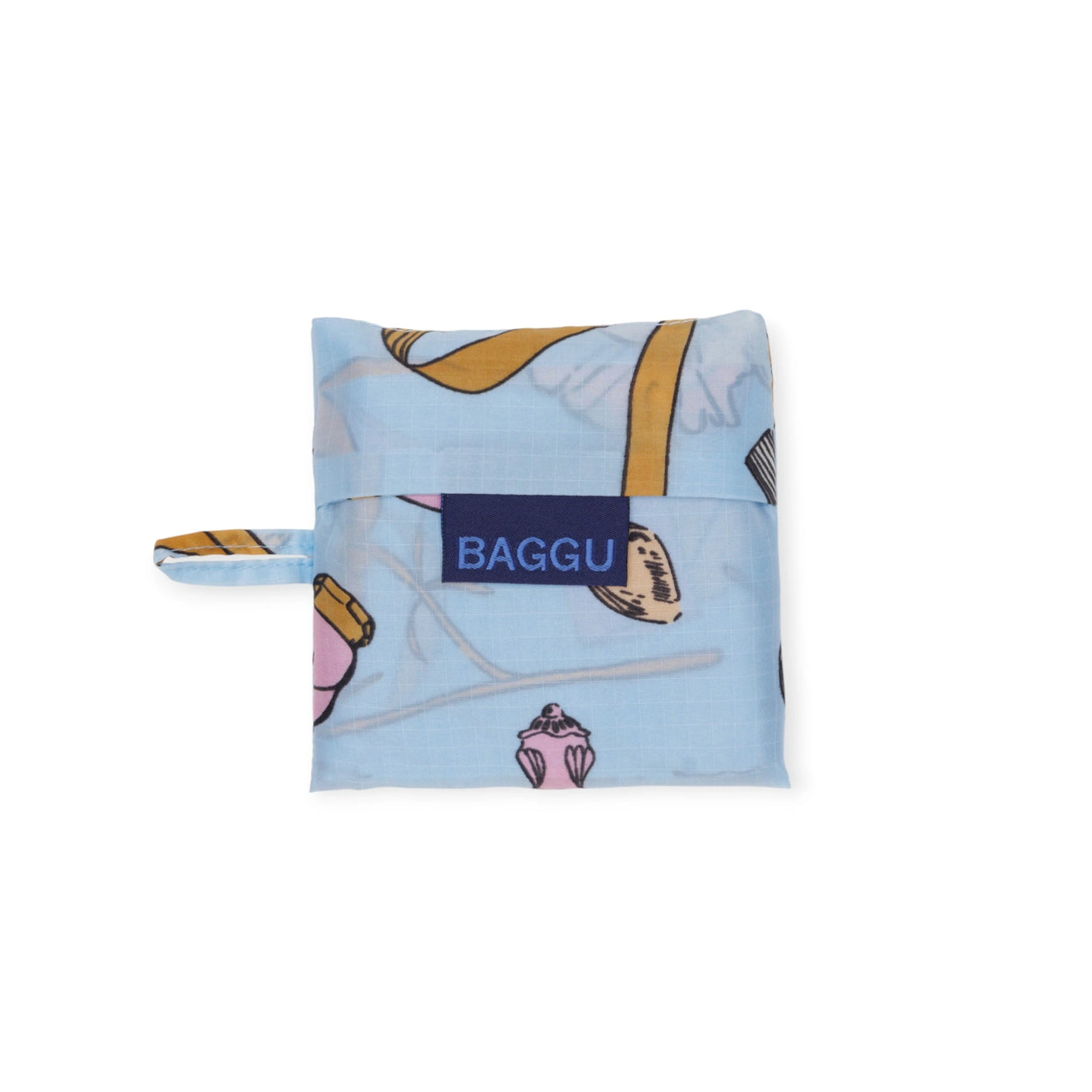 The Baby Baggu Reusable Bag - Get Ready With Me is a folded bag made from recycled nylon with a light blue background, featuring prints of brushes and pink items. It includes a small handle and "BAGGU" on the front, making it perfect for chic errands. Brand: Baggu.