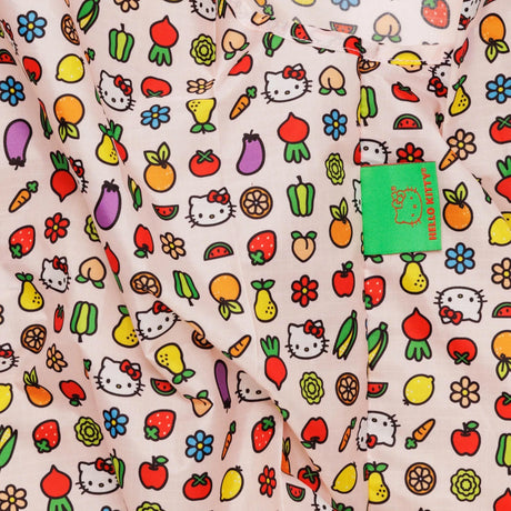 The Baby Baggu Bag - Hello Kitty Icons by Baggu showcases a light background adorned with vibrant fruits, vegetables, flowers, and an adorable cartoon cat design. A green label highlights its status as a limited edition item.