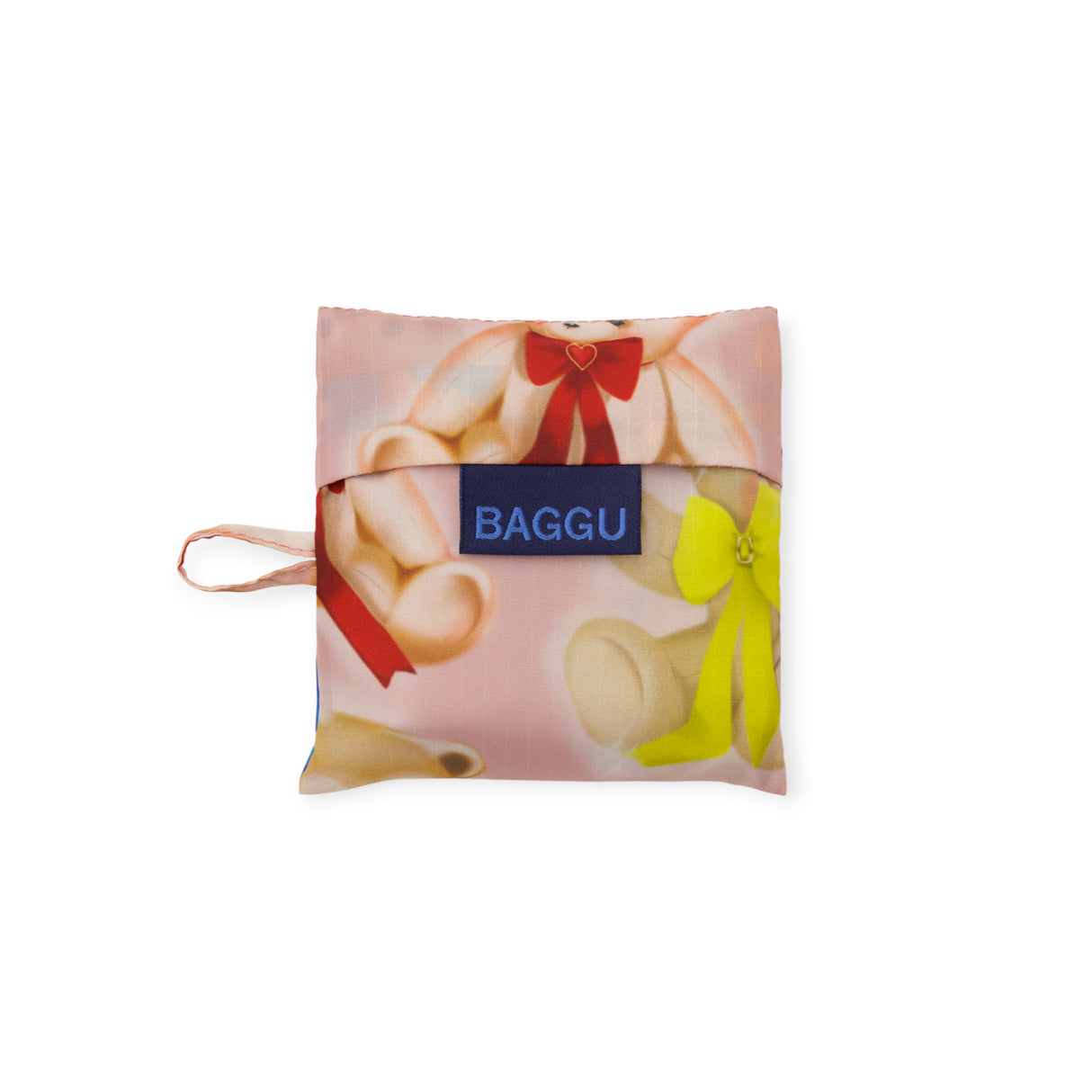 Compact folded Baby Baggu bag in soft pink with teddy bears wearing red and yellow bows and blue Baggu label