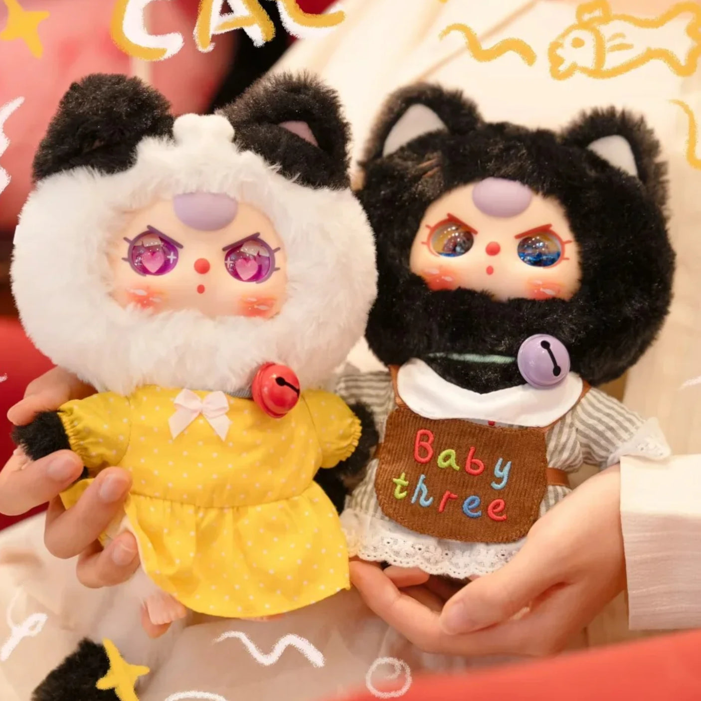 Two plush animal keychains with colorful eyes: yellow dress cat and white shirt bear; rings