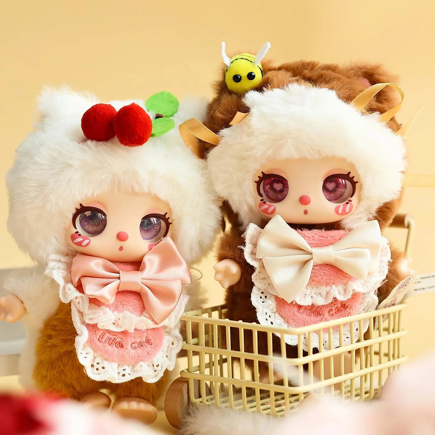 Baby Three - Liila's Chef Kitten Blind Box plush dolls in fluffy onesies with bows, one holding a shopping basket with bee accessory.