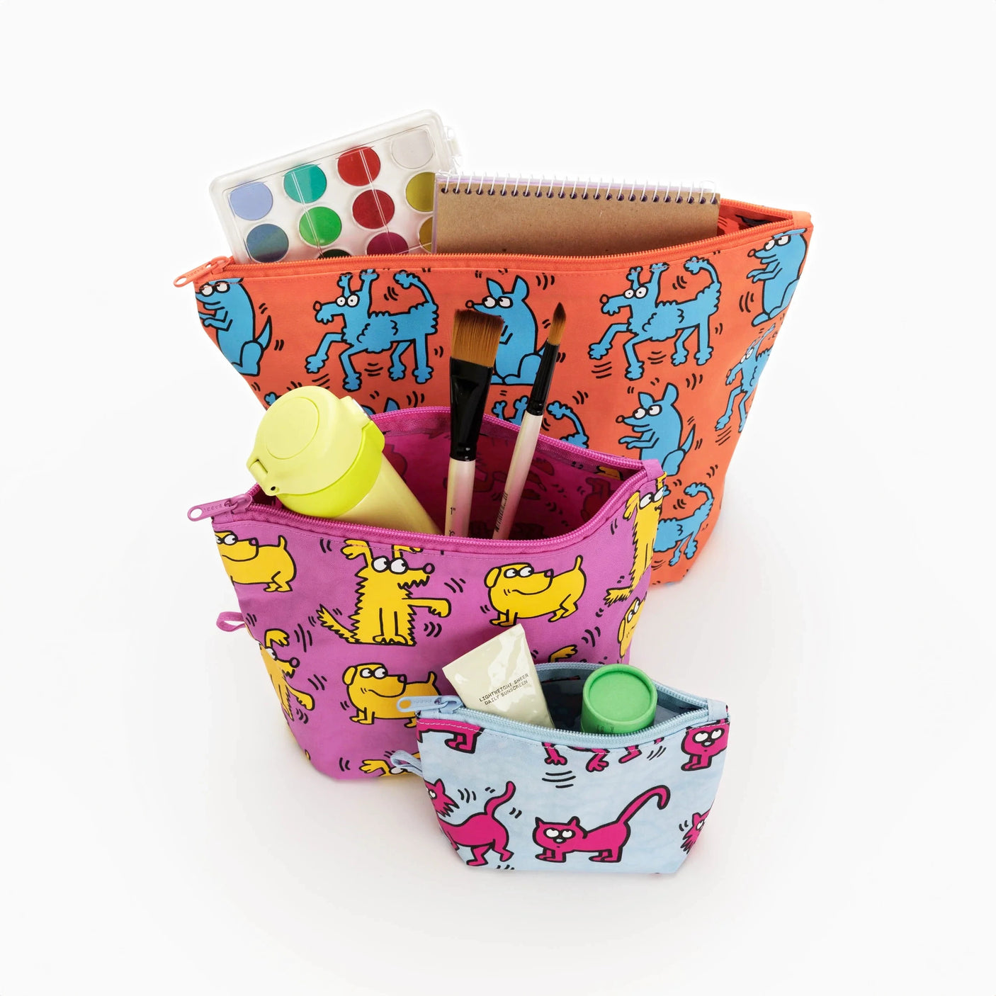 Three vibrant Baggu Go Pouch Set - Keith Haring sets, adorned with colorful dog prints, contain art supplies such as paint, brushes, a notebook, and a water bottle. Made from recycled materials by Baggu, they are both eco-friendly and artistically striking.