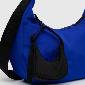 Crescent nylon bag with lapis blue body, black side strap, and zipper trim