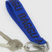 The Baggu Logo Keychain, made from recycled nylon webbing, displays "BAGGU" in bold black on blue fabric and attaches to a set of silver keys with a durable metal clip for secure fastening.