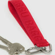 The Baggu Logo Keychain - Peony is a red fabric keychain strap made from recycled nylon, featuring "MCM BACK" text, and includes metal keys and a carabiner, similar to the sleek Baggu style.