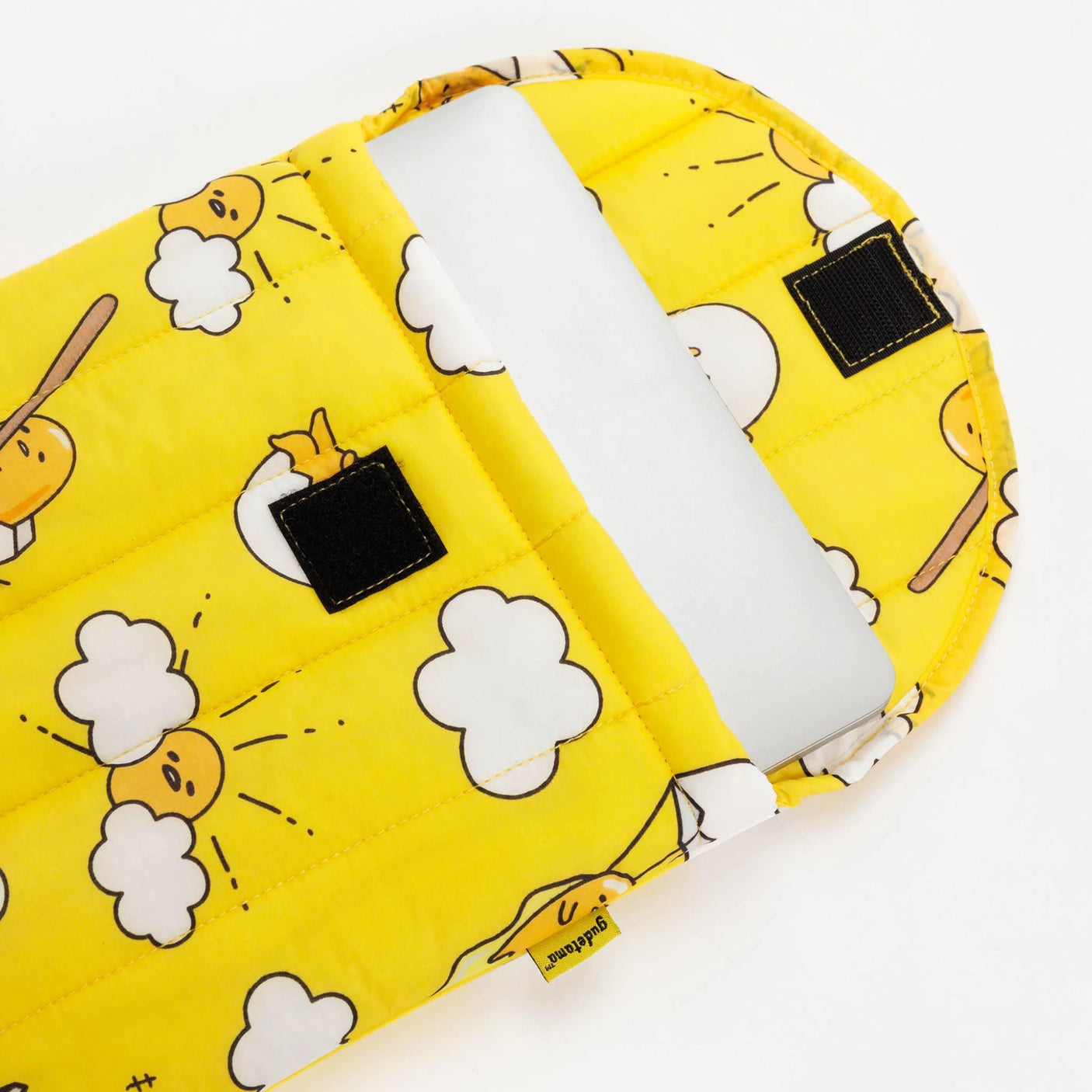 Yellow Gudetama x Baggu Puffy Laptop Sleeve - 13"/14" with a whimsical cartoon fried eggs pattern and two secure hook-and-loop fasteners.