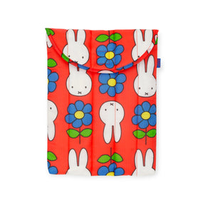 The Baggu Miffy x Baggu Puffy Laptop Sleeve 13"/14" is a red quilted case with a flap, decorated with white cartoon rabbits and blue flowers with green leaves.