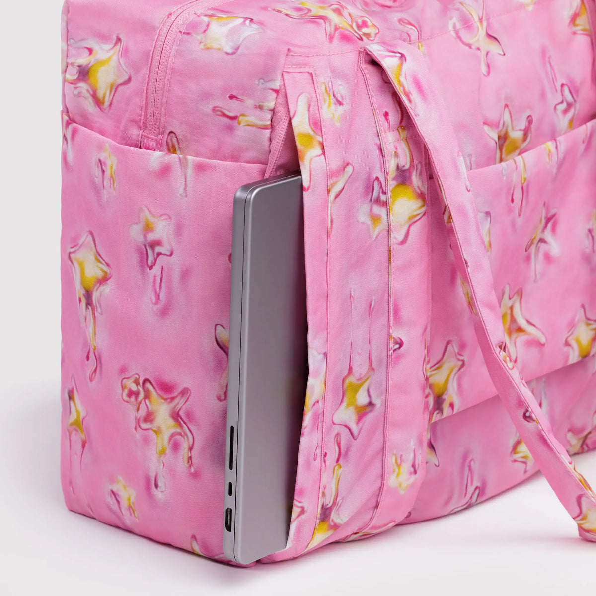 Pink star-print carry-on bag with front zip pocket holding smartphone