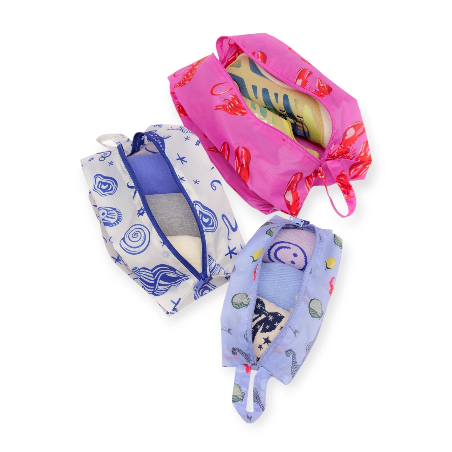 Baggu Storage & Travel Set - Sea Creatures by Baggu features three zippered pouches with playful sea creature prints, arranged on a white background and neatly filled with folded clothes.