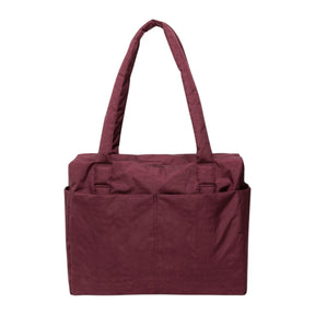 The Baggu Small Cloud Carry-on in mahogany by Baggu is a maroon tote with two handles, two large front pockets, and a rectangular shape—ideal as a versatile travel bag, shown against a white background.