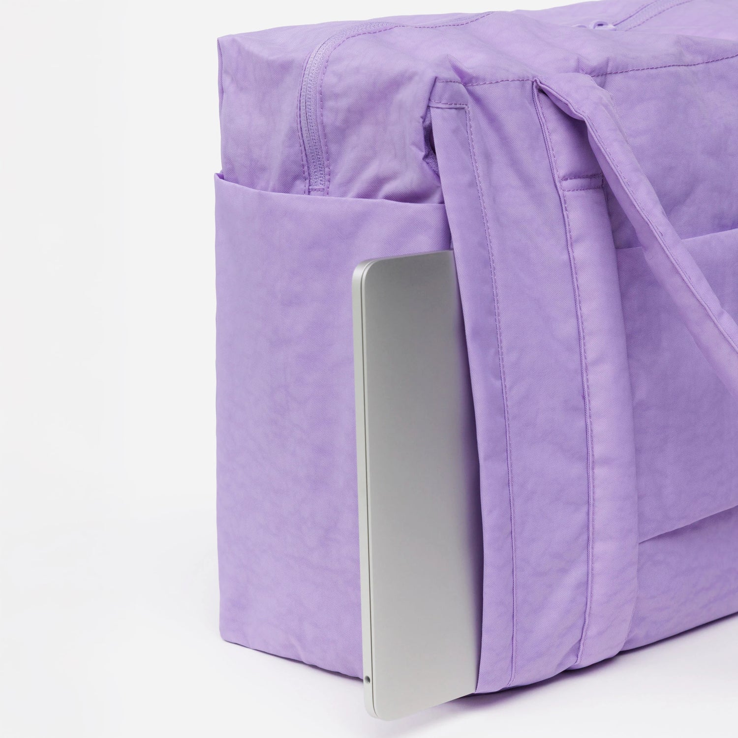 A Baggu Small Cloud Carry-on in Wisteria, shown with a laptop partially in its outer pocket, photographed against a white background.