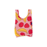 The Baby Baggu Reusable Bag from Baggu features a pink background with a playful pattern of vibrant red apples and yellow bananas, all crafted from recycled nylon.