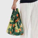 A person holds a Baggu Baby Baggu Reusable Bag featuring the vibrant "Orange Tree" design, reminiscent of a lively orchard laden with ripe citrus.