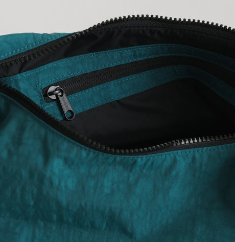 A teal Hello Kitty x Baggu Medium Nylon Crescent Bag features a partially opened top revealing a sleek black interior and an additional inner zip pocket.