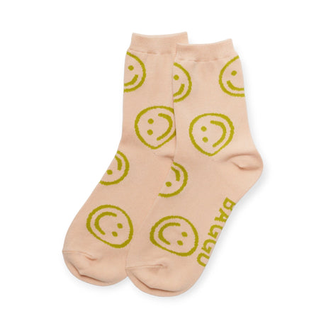 The Baggu Crew Sock - Light Pink Happy is made from cosy and soft bamboo rayon, featuring a light pink hue adorned with green smiley face patterns and playful text on the bottom.