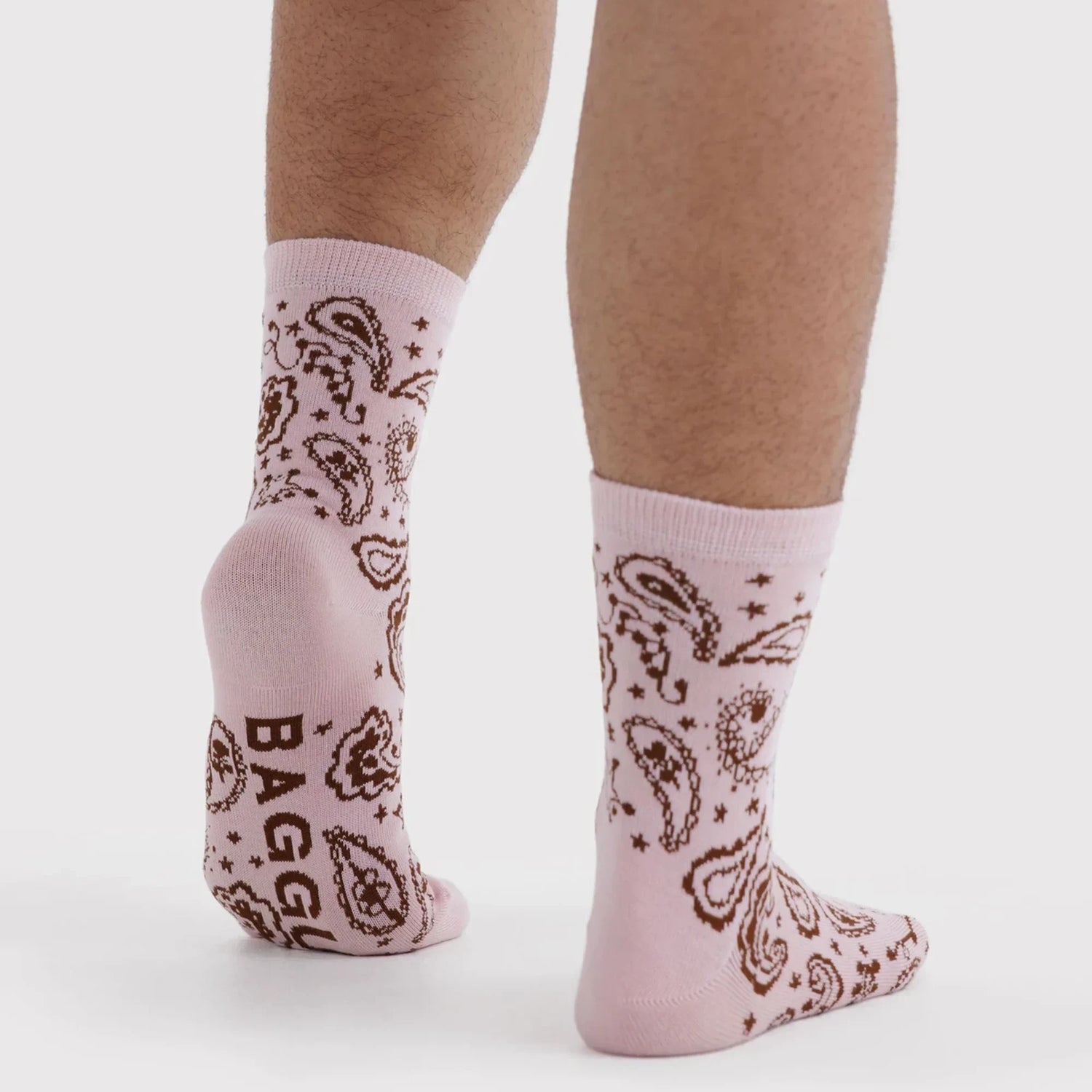 Pink crew socks with brown paisley and star pattern, worn with bare legs