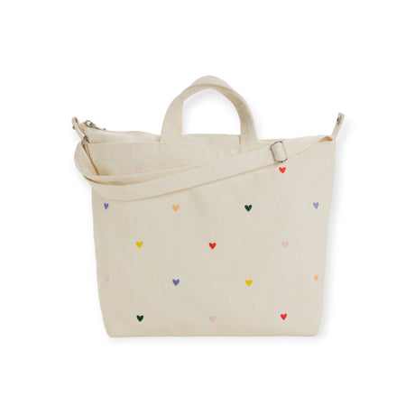 The Baggu Duck Bag Medium in cream by Baggu showcases an adjustable strap and delightful embroidered heart patterns.