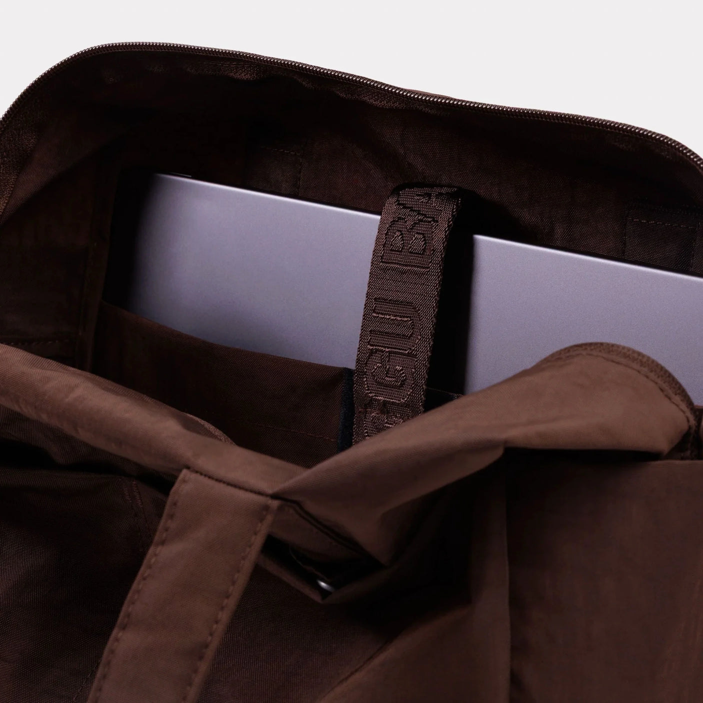 Brown canvas tote bag interior with zipper pocket and fabric logo patch