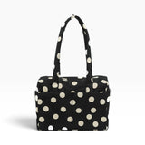 Black tote bag with cream polka dots and top handle, open-top pouch style