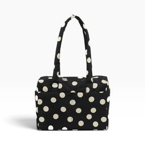 Black tote bag with cream polka dots and top handle, open-top pouch style