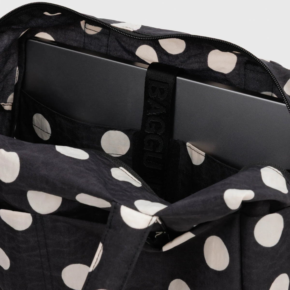 Interior of black polka-dot tote with zip top, padded lining and inner pockets