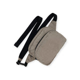 The Baggu Fanny Pack Dove, a crossbody bag made from durable nylon, showcases a beige design with a black adjustable strap and a zippered main compartment, all elegantly displayed on a white background.