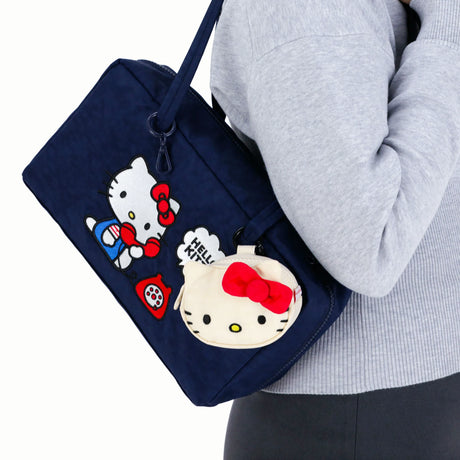 A person carries a navy blue bag adorned with the Hello Kitty x Baggu Bag Charm from Baggu, highlighting their love for cute Hello Kitty accessories.