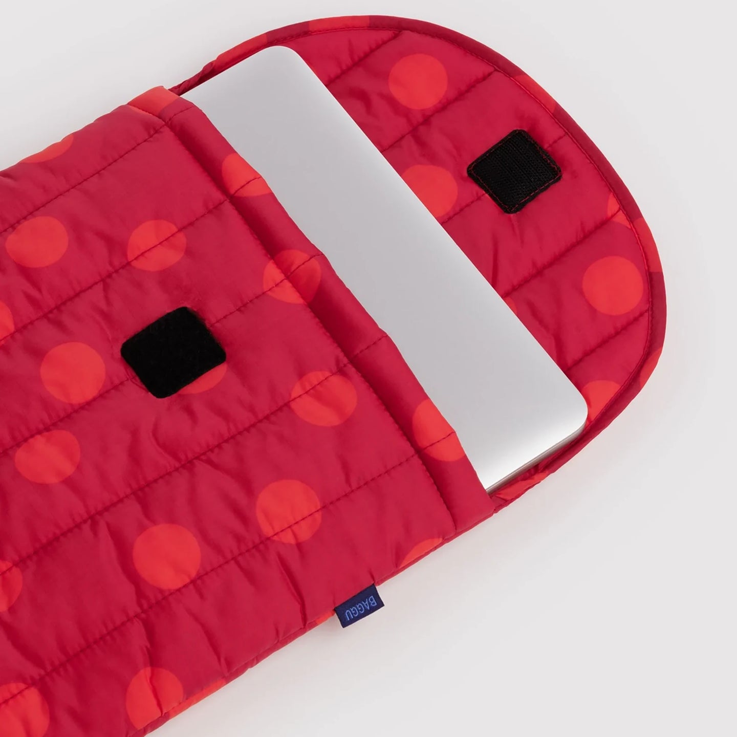 Red quilted laptop case with red polka dots, open top, black patch details