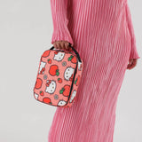 A person in a pink pleated dress holds the Hello Kitty x Baggu Lunch Bag, which features Hello Kitty and strawberry patterns and is crafted from recycled polyester.