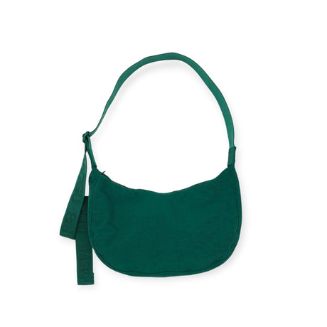 The Baggu Medium Nylon Crescent Bag - Cypress includes an adjustable tonal logo strap and a delightful decorative ribbon on the handle.