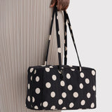 Medium nylon bowler bag with black and cream polka dots, side view with handles