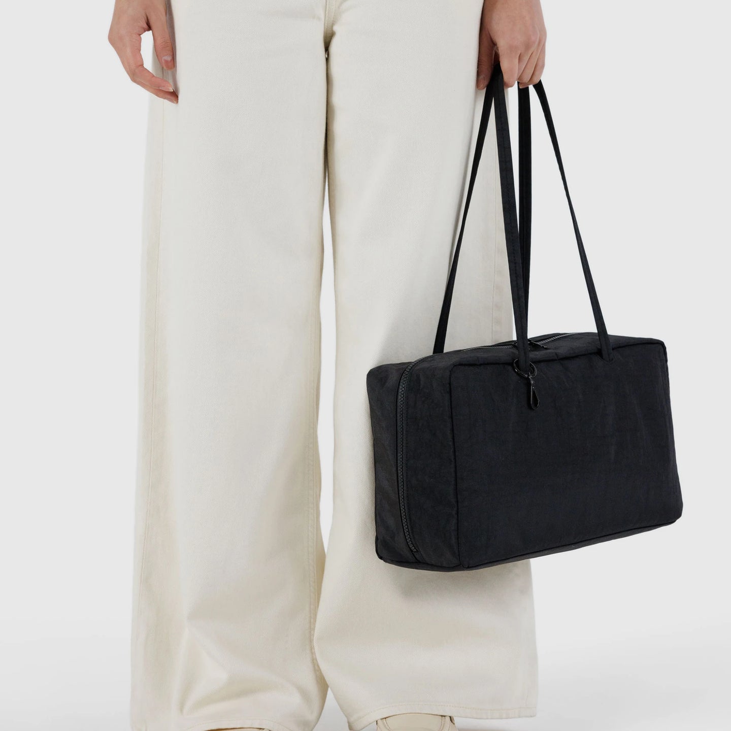 Black medium nylon bowler bag with top handles, carried at shoulder length
