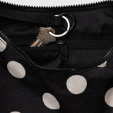 Black nylon polka dot crescent bag close-up with zipper and metal ring pull.