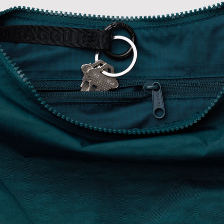 Close-up of dark teal fabric zipper pocket with attached black key ring holding two silver keys