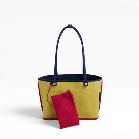 Nylon reversible tote bag with yellow lining, navy handles, and red pouch