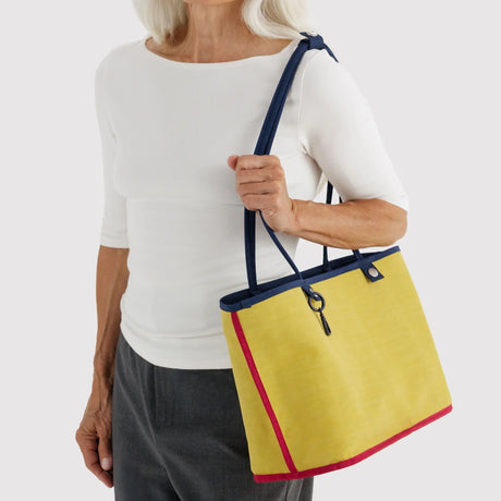 Reversible nylon tote bag with yellow lining and navy handles, carried