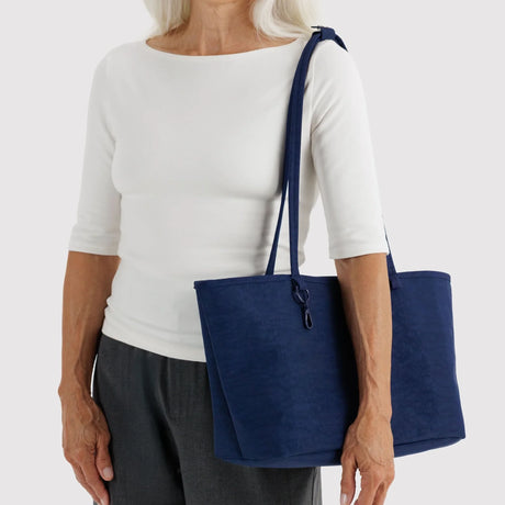 Nylon reversible tote bag with navy exterior, carried by handles