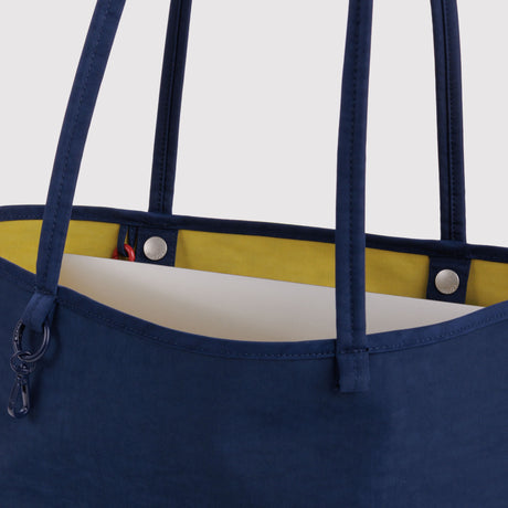Reversible tote bag close-up: navy strap seams and yellow interior lining