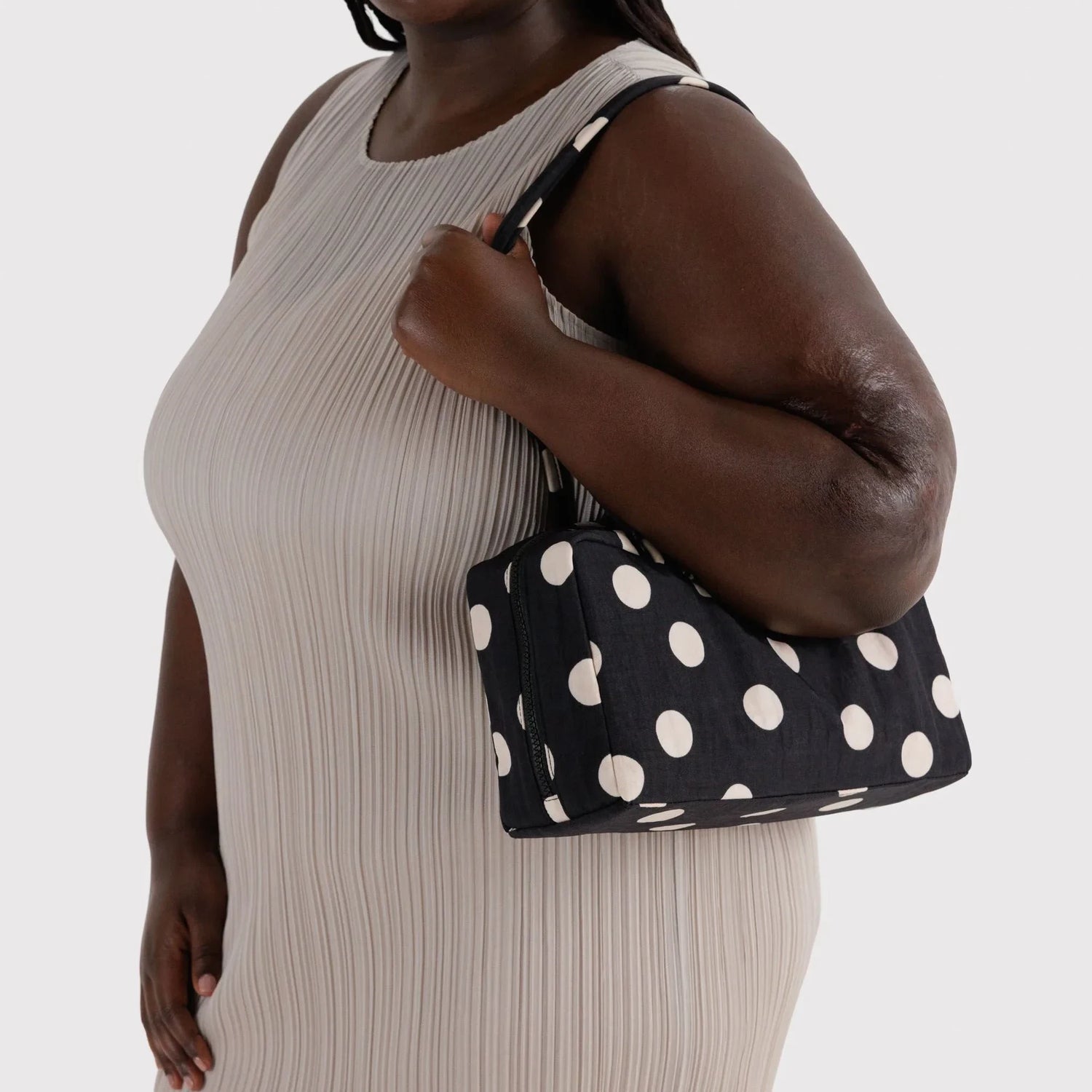 Black nylon bowler bag with cream polka dots, held by model.