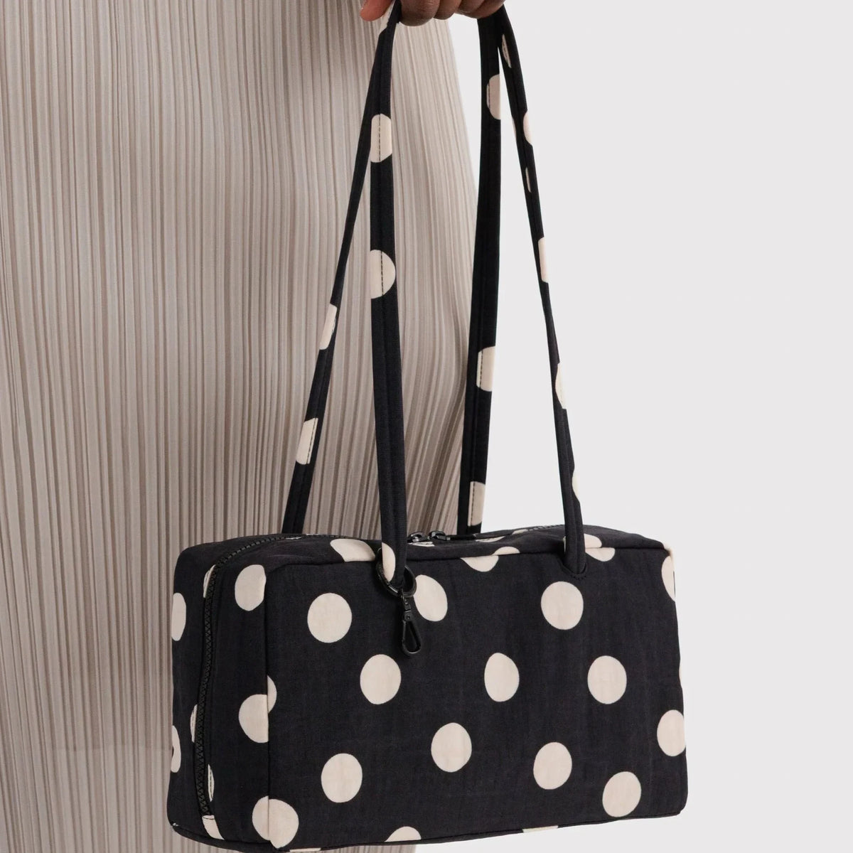 Black nylon bowler bag with cream polka dots, long handles, side view.