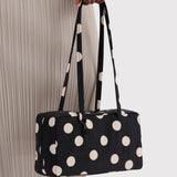 Black nylon bowler bag with cream polka dots, long handles, side view.