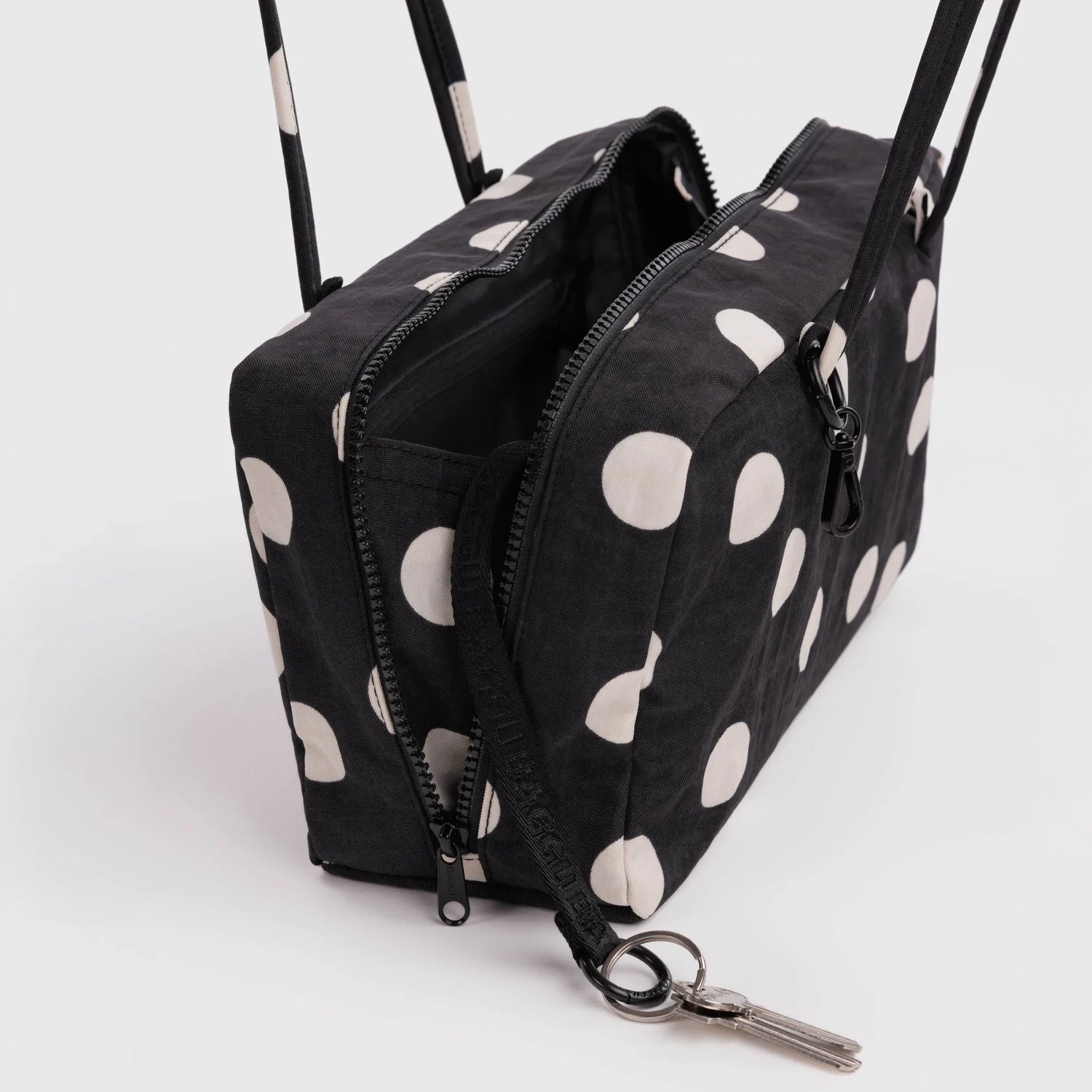 Black nylon bowler bag with cream polka dots, open top showing zippers and key clip.