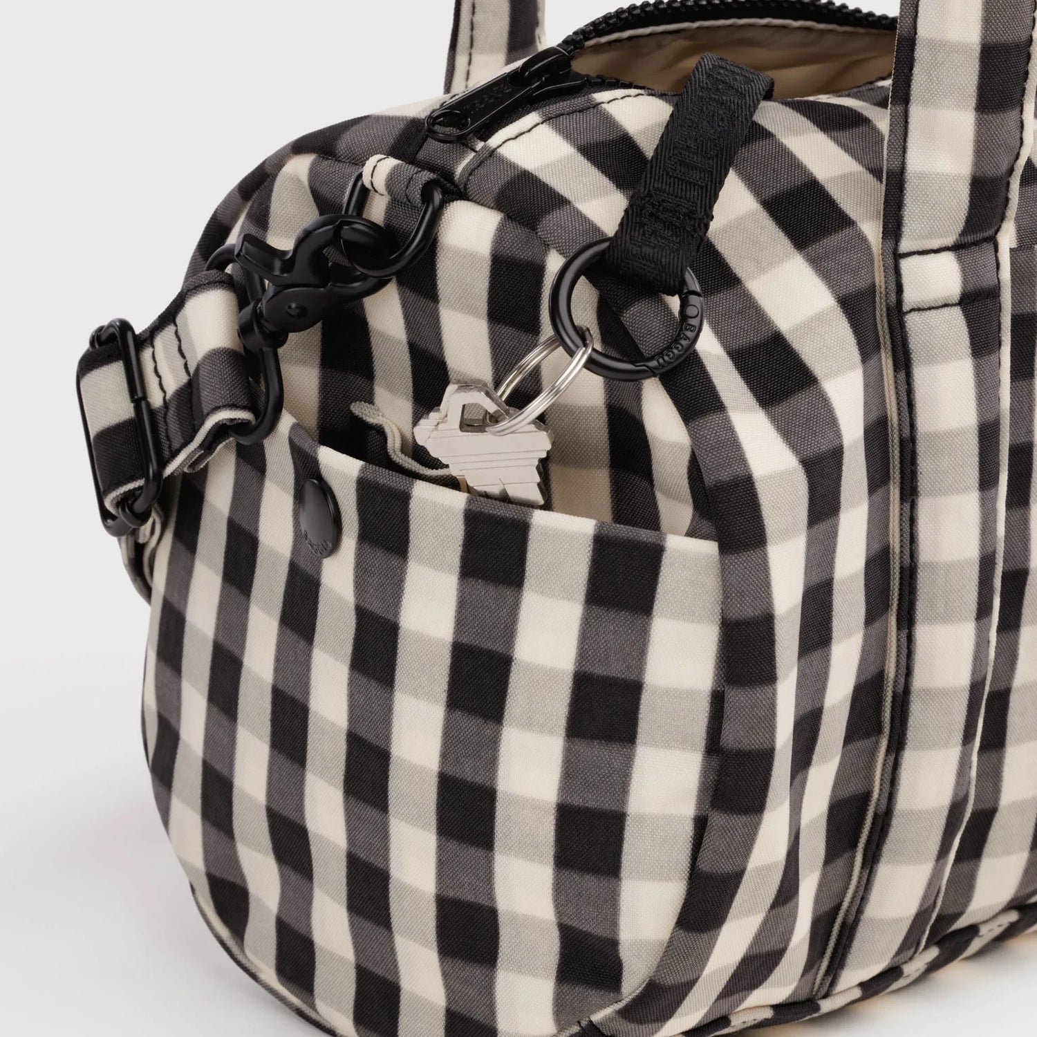 Black-and-cream gingham duffle bag with metal rings, key clip, and adjustable strap