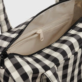 Open interior of black-and-cream gingham duffle bag with beige lining and zipper